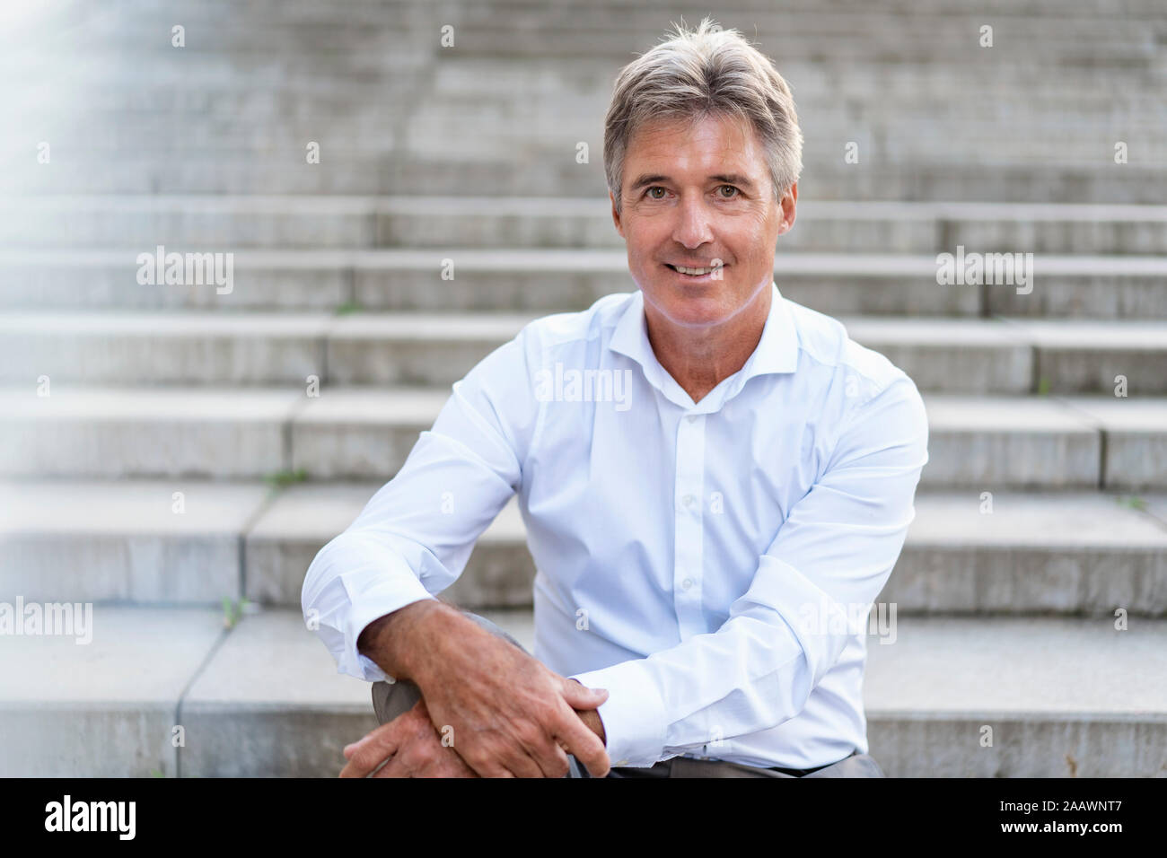 Portrait of confident mature businessman sitting on stairs Stock Photo