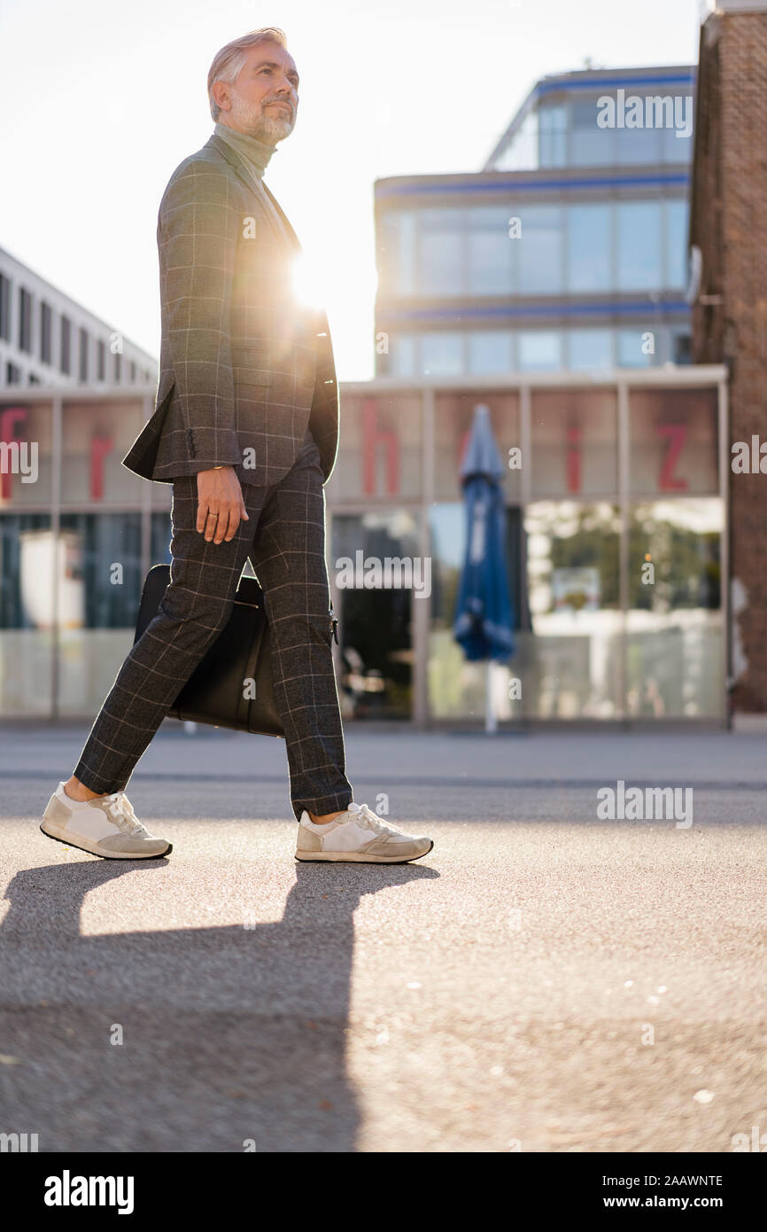 Fashionable mature businessman with bag on the go in the city Stock Photo