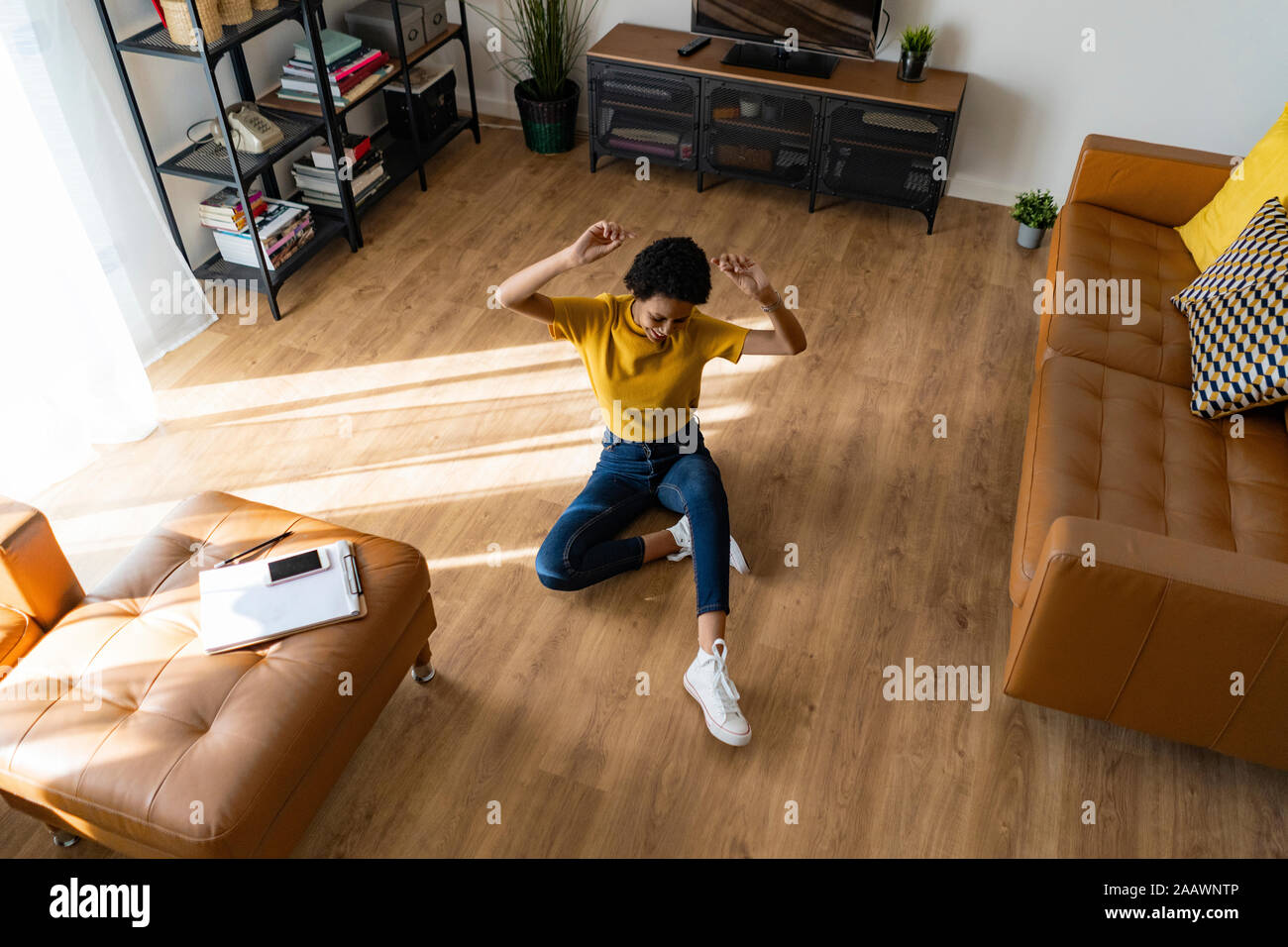 Excited young woman sitting on the floor at home Stock Photo