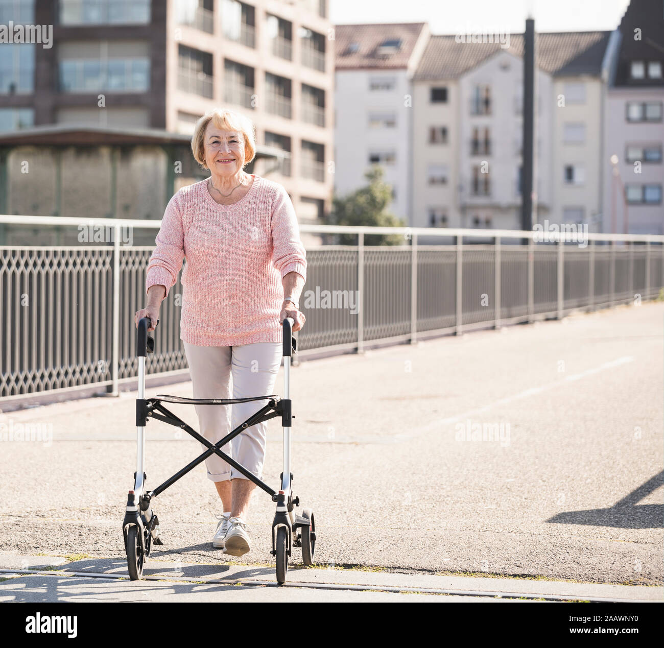 Senior woman with wheeled walker on footbridge Stock Photo