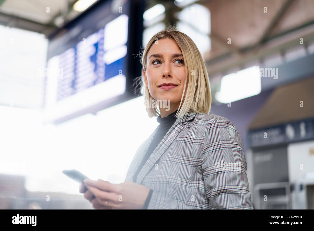 Young businesswoman with mobile phone at the train station Stock Photo