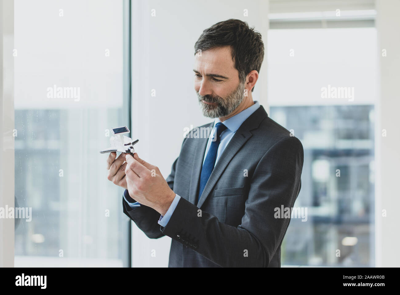 Smiling mature bussinessman holding space shuttle model Stock Photo