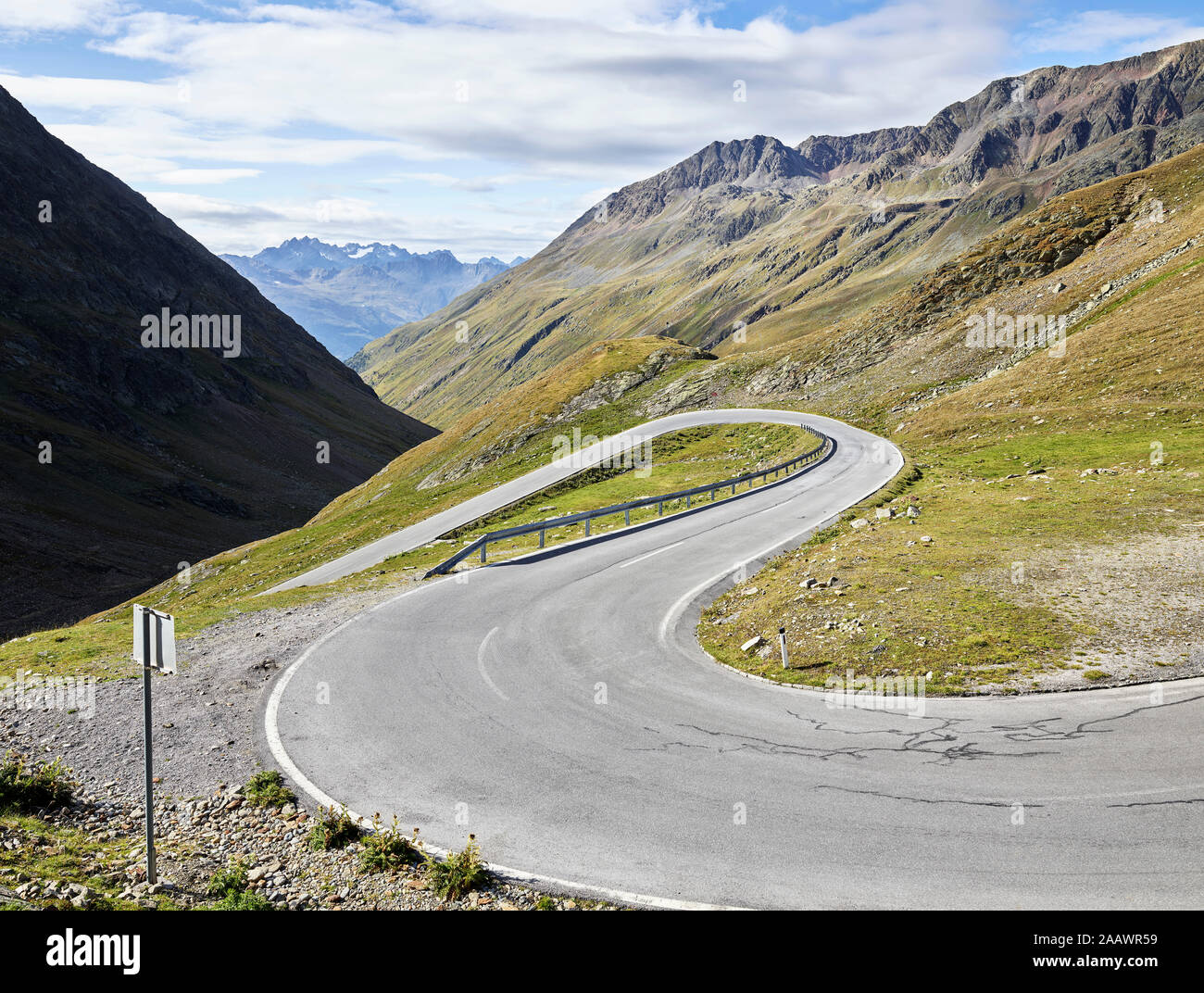 Winding road on mountain against cloudy sky during sunny day, Tyrol State, Austria Stock Photo