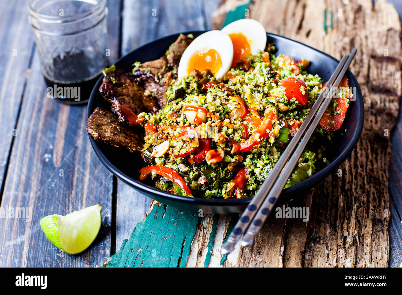 Thai style fried broccoli rice (shredded broccoli) with beef slices, eggs, and spicy sauce (ketogenic diet, paleo diet, low carb) Stock Photo