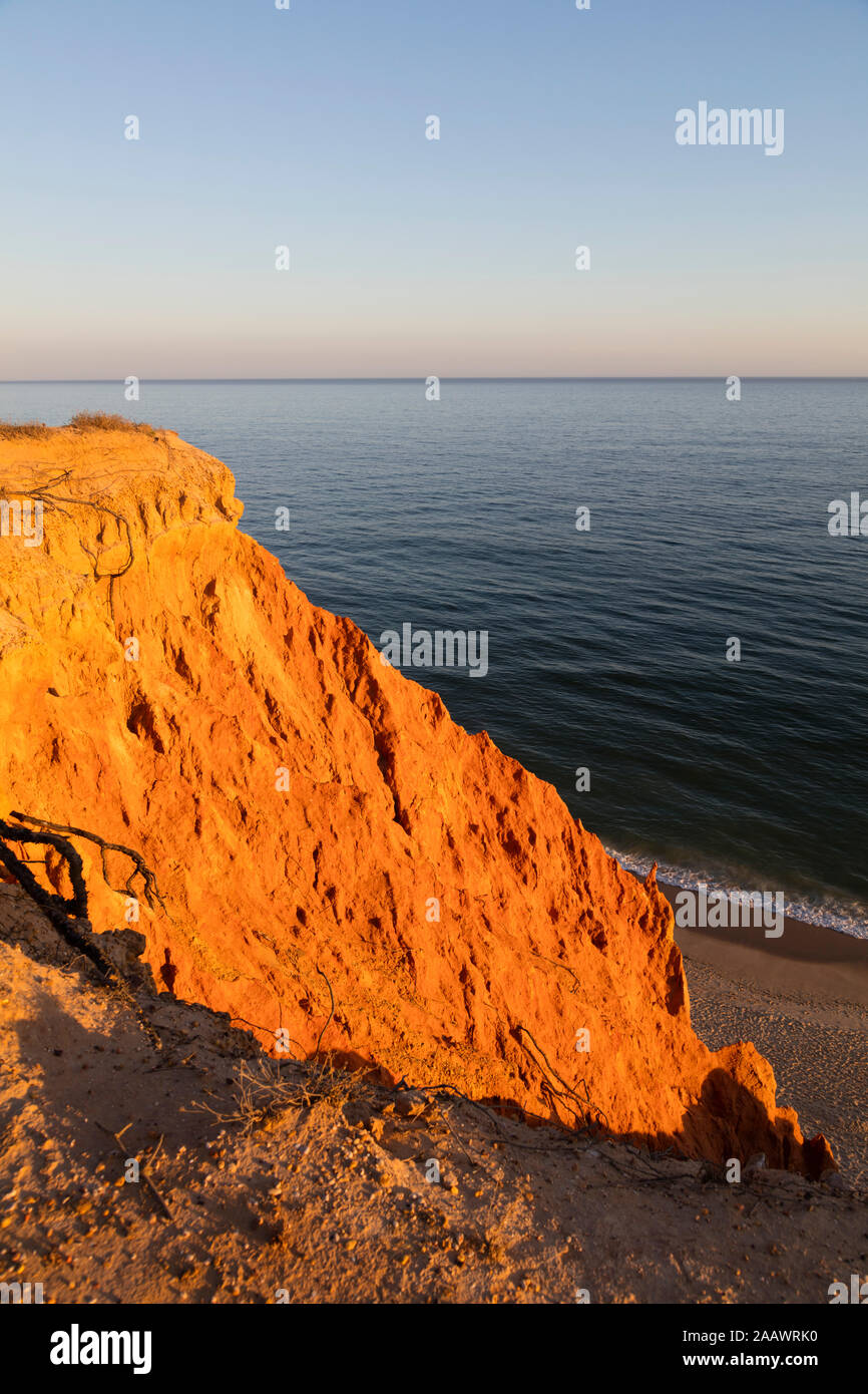 Rocky sandstone coast against clear sky during sunset, Algarve, Portugal Stock Photo