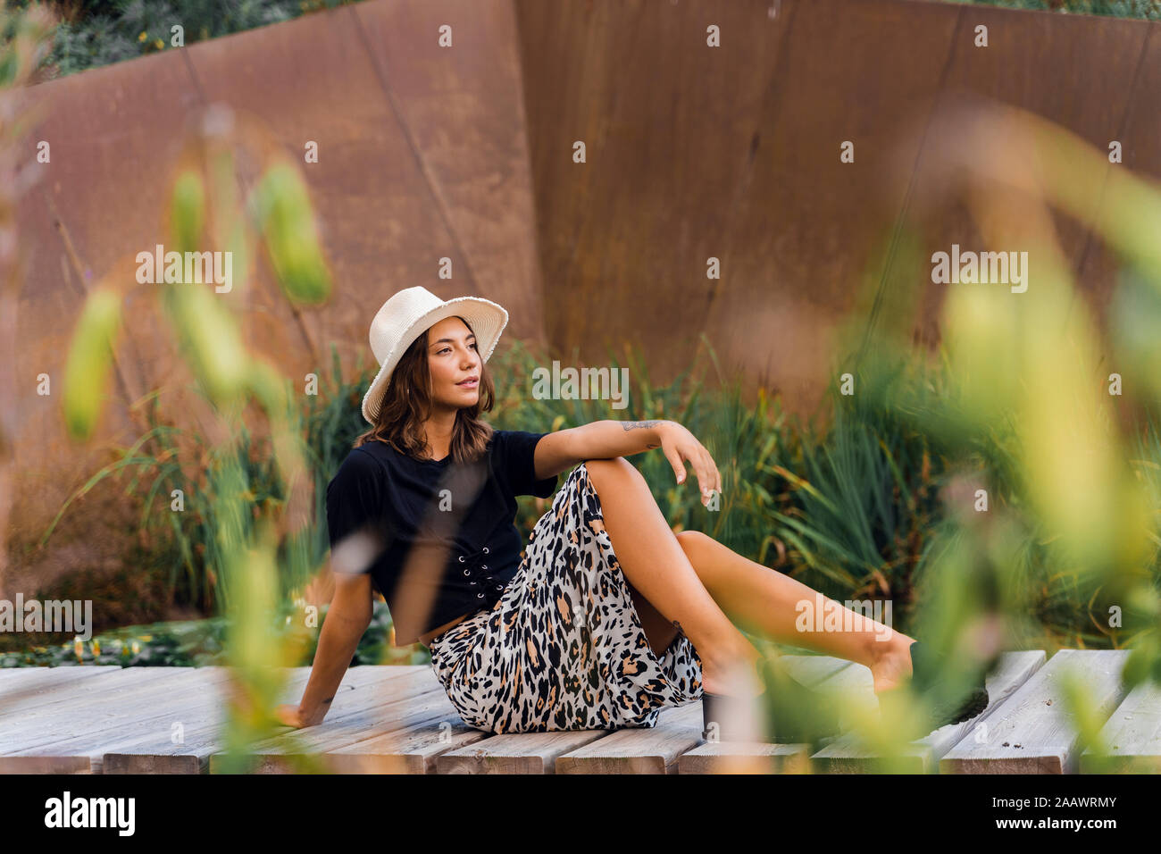 Portrait of fashionable young woman relaxing on boardwalk Stock Photo