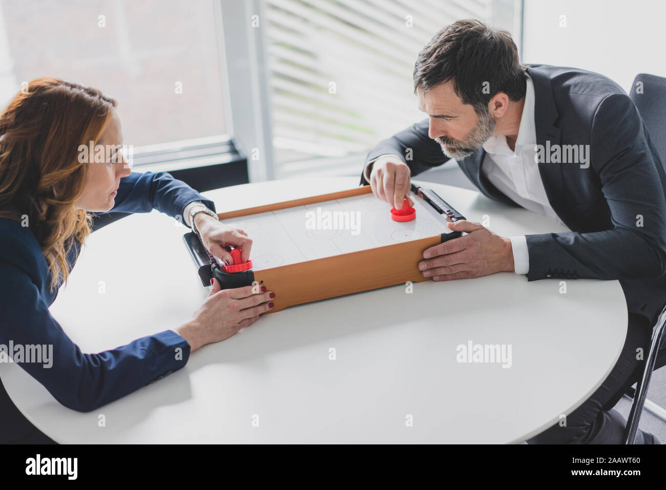 Businesswoman and businessman playing air hockey in office Stock Photo