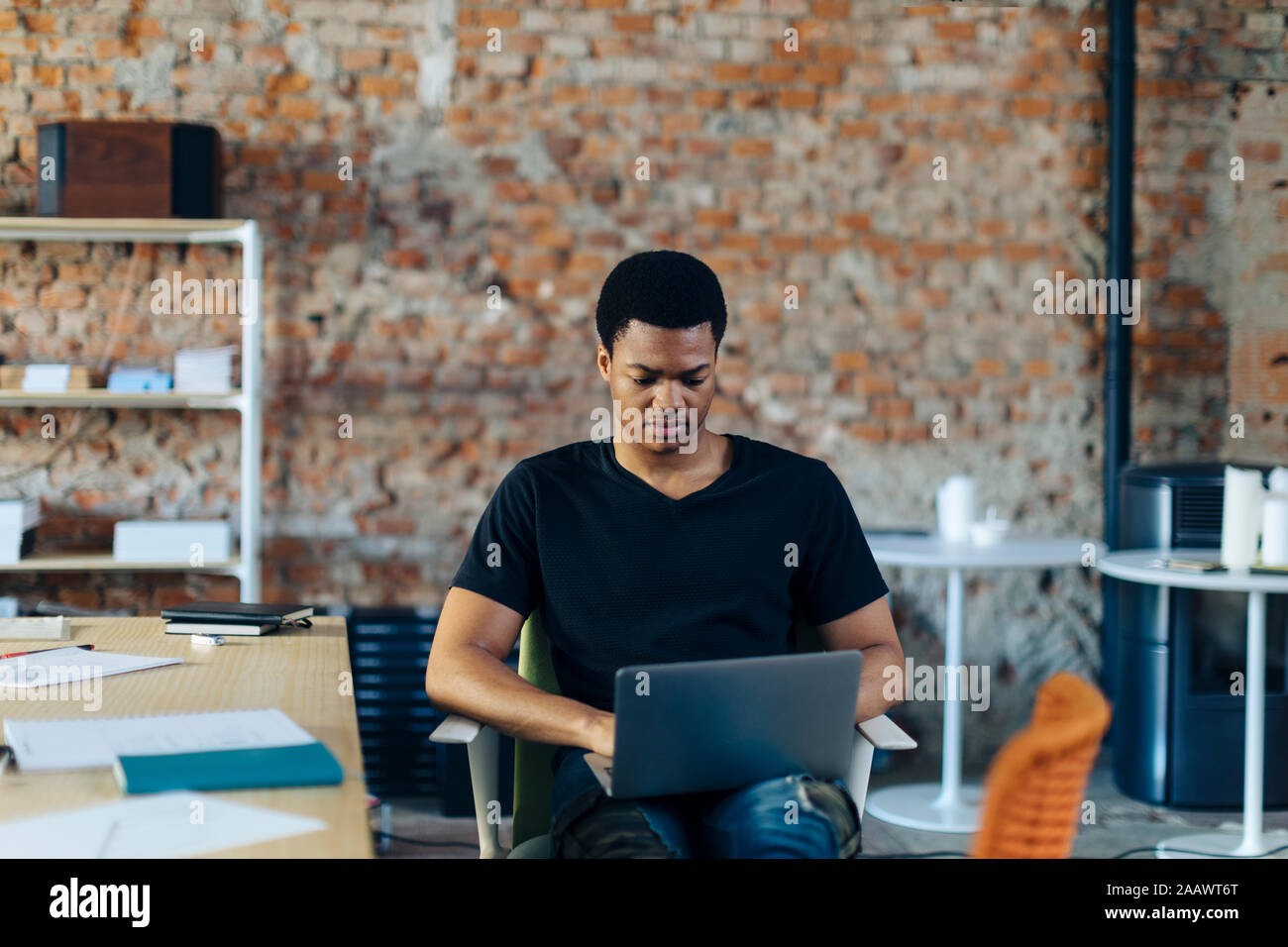 Young man sitting on chair using laptop Stock Photo