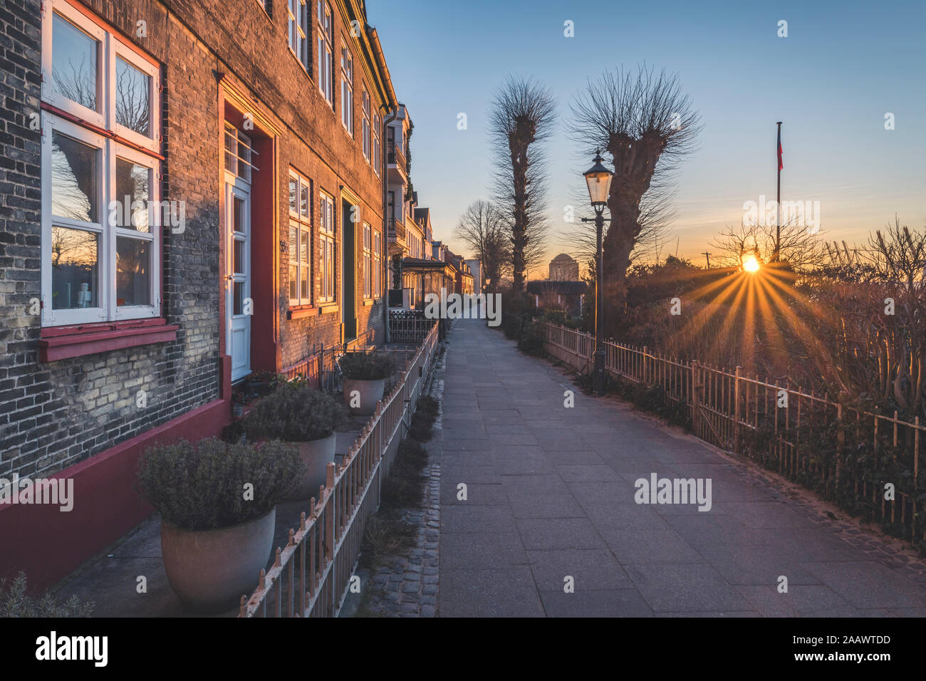 Diminishing perspective of empty footpath by buildings against sky during sunrise, Hamburg, Germany Stock Photo