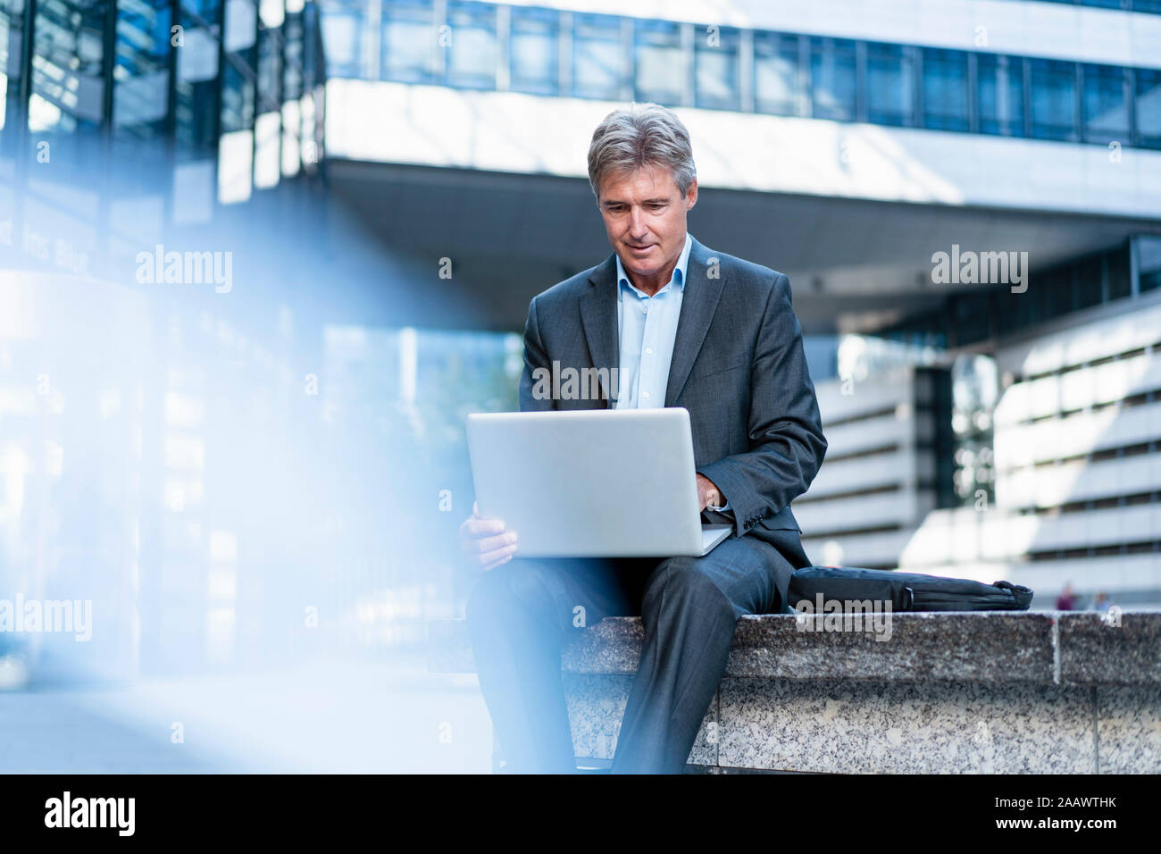 Mature businessman using laptop in the city Stock Photo