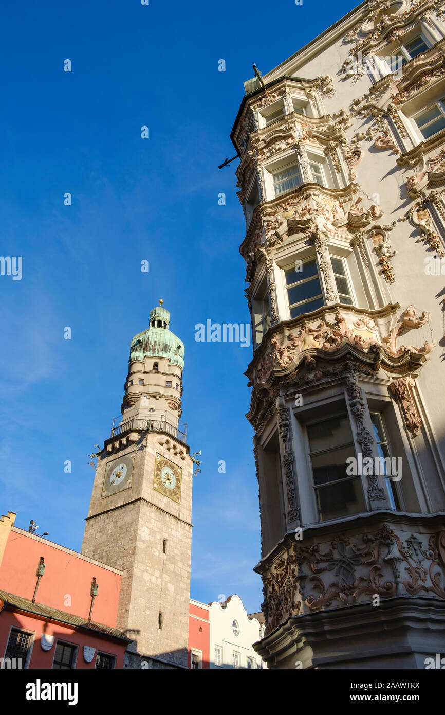 Low angle view of Stadtturm and Helbling House against blue sky at Innsbruck, Austria Stock Photo