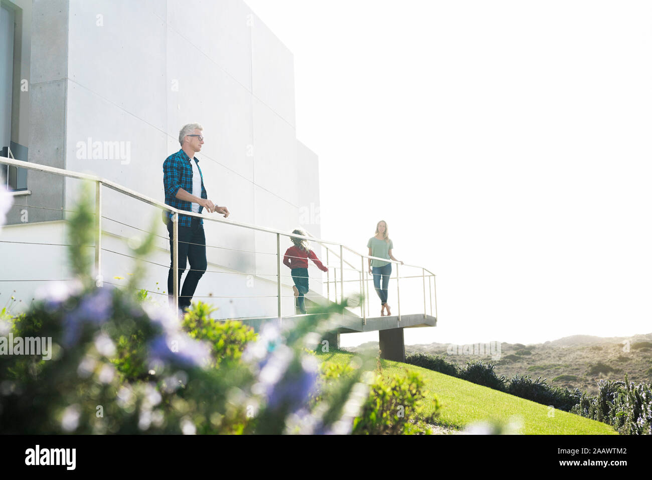 Casual man with his family standing in front of modern home looking at the landscape Stock Photo