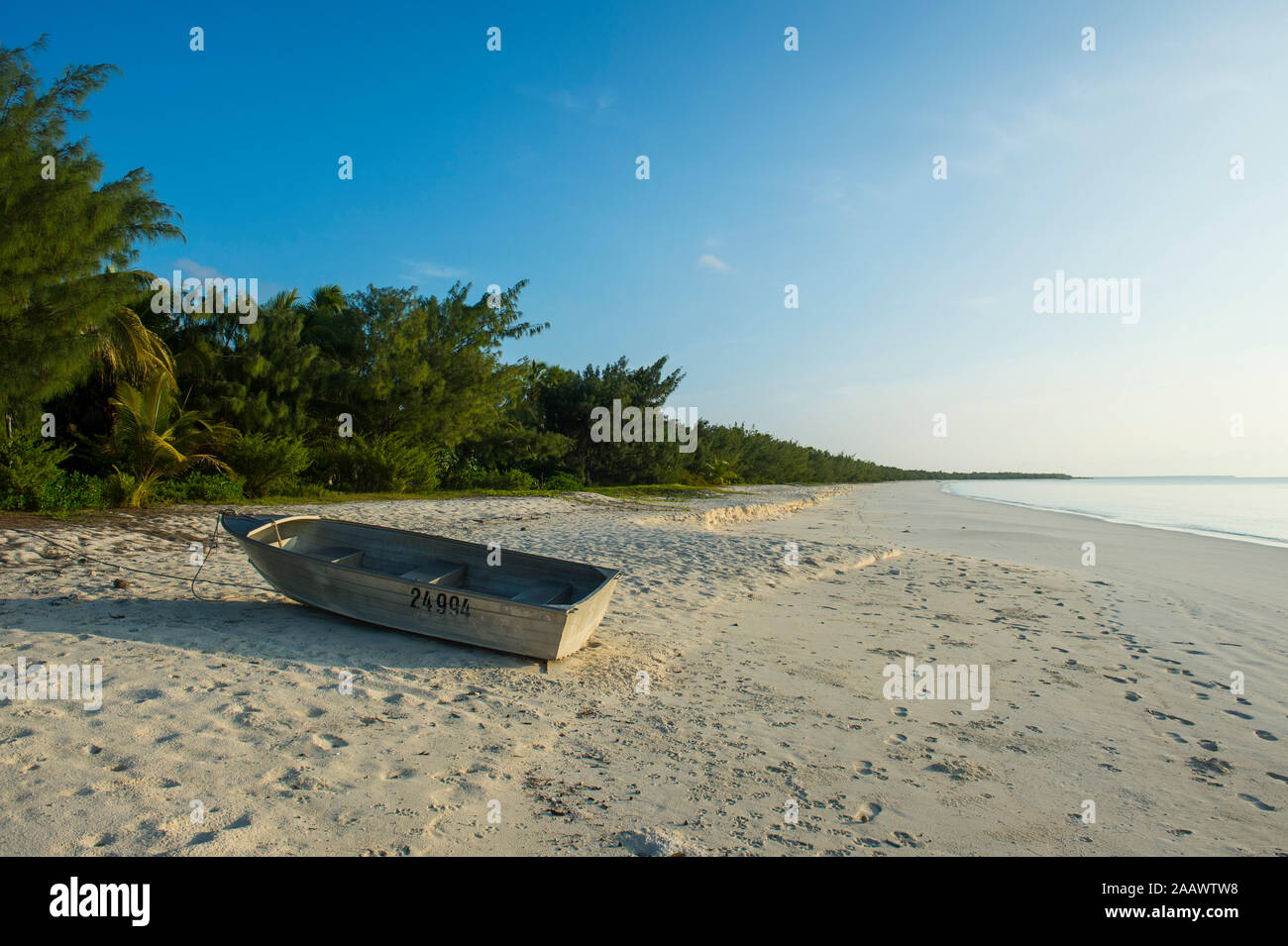 Boat moored at white sand beach during sunset, Ouvea, Loyalty Islands, New Caledonia Stock Photo