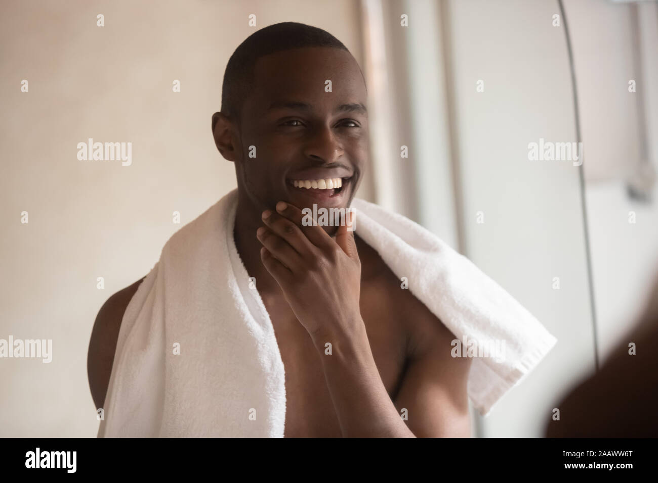 Smiling biracial man do daily facial routine in bathroom Stock Photo