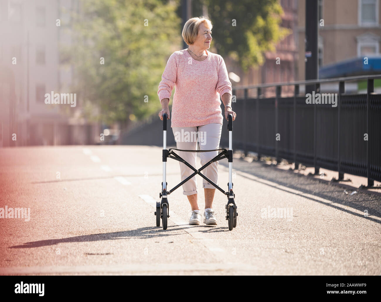 Senior woman with wheeled walker on footbridge Stock Photo