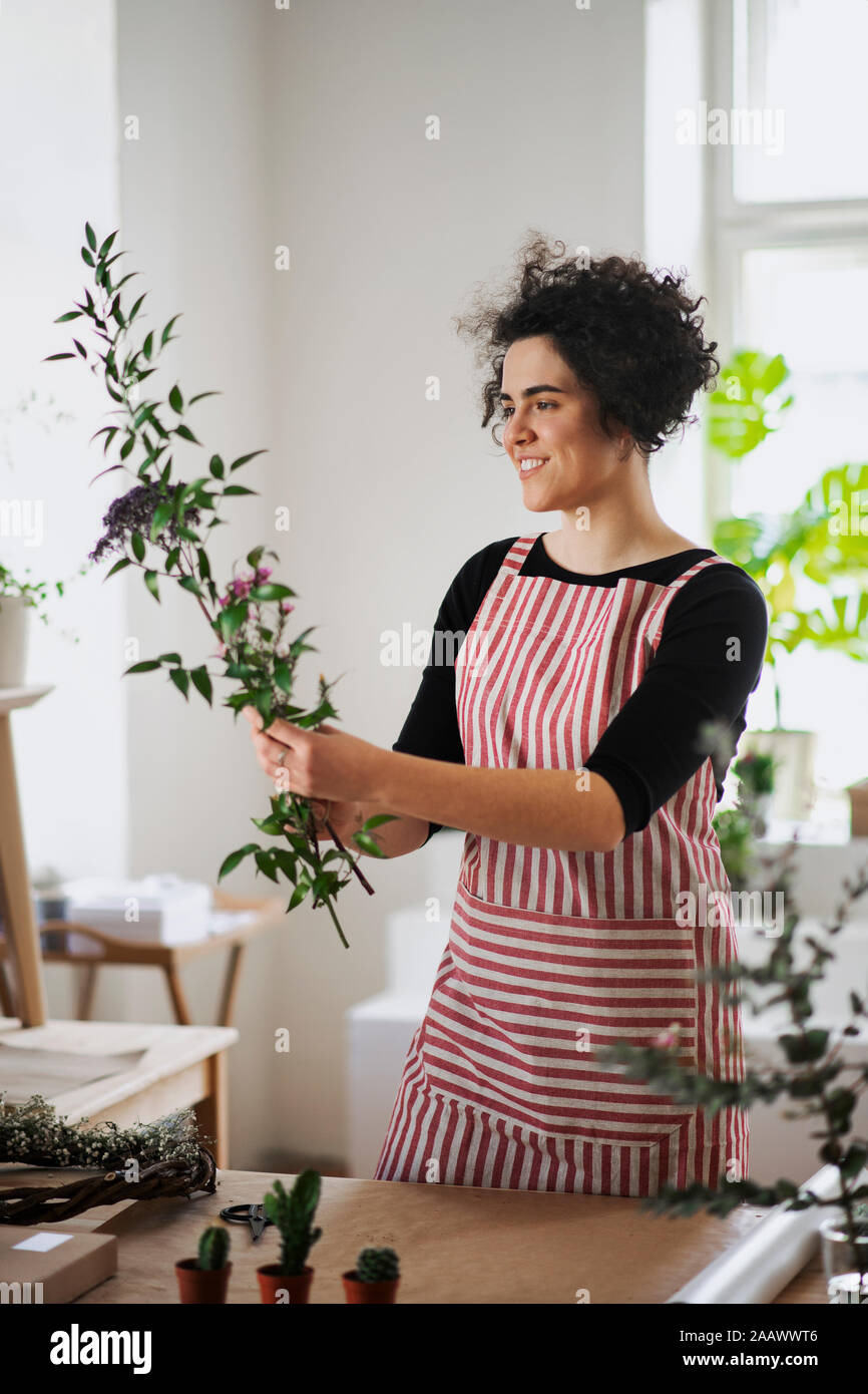 Smiling young woman arranging flowers in a small shop Stock Photo - Alamy