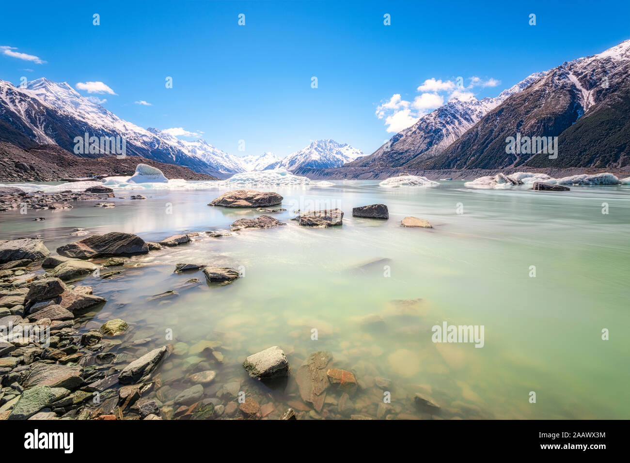 New Zealand, South Island, Rocky shore of Tasman Lake with icebergs, glacier and mountain backdrop Stock Photo