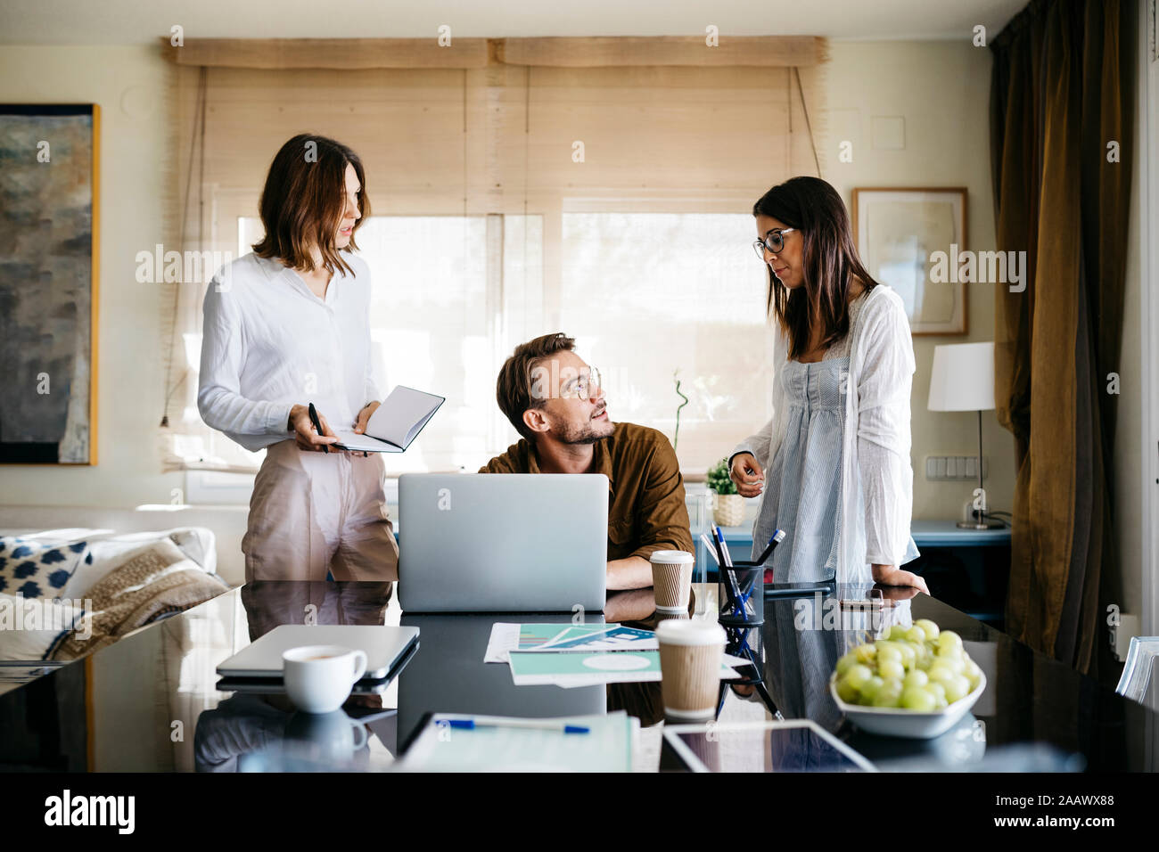 Coworkers working together on table at home Stock Photo