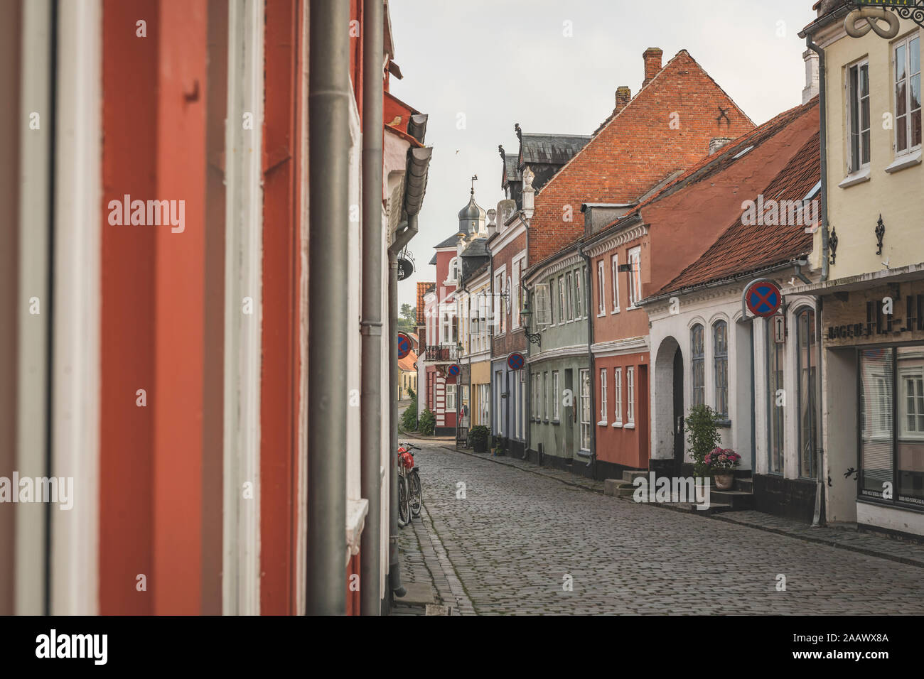 Denmark, Aeroe, Aeroskobing, Colorful traditional townhouses seen over empty street Stock Photo