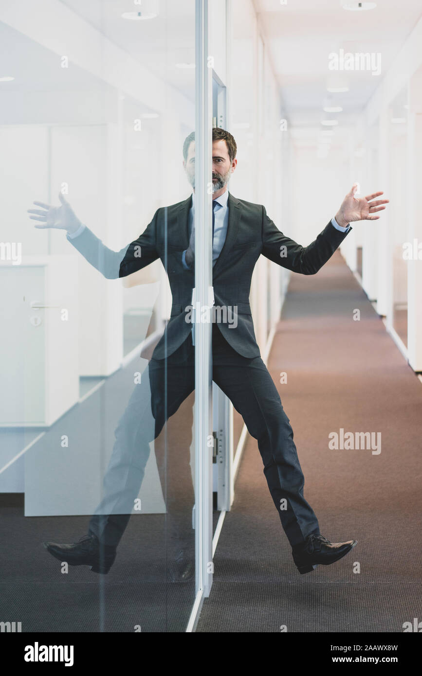 Mature bussinesman reflected in glass wall in office Stock Photo