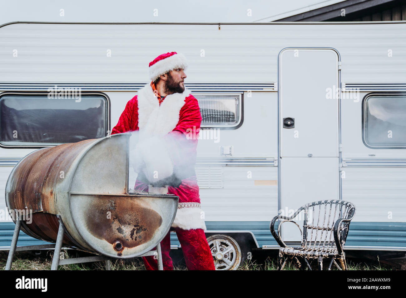 Santa claus preparing a barbecue in front of a camper Stock Photo