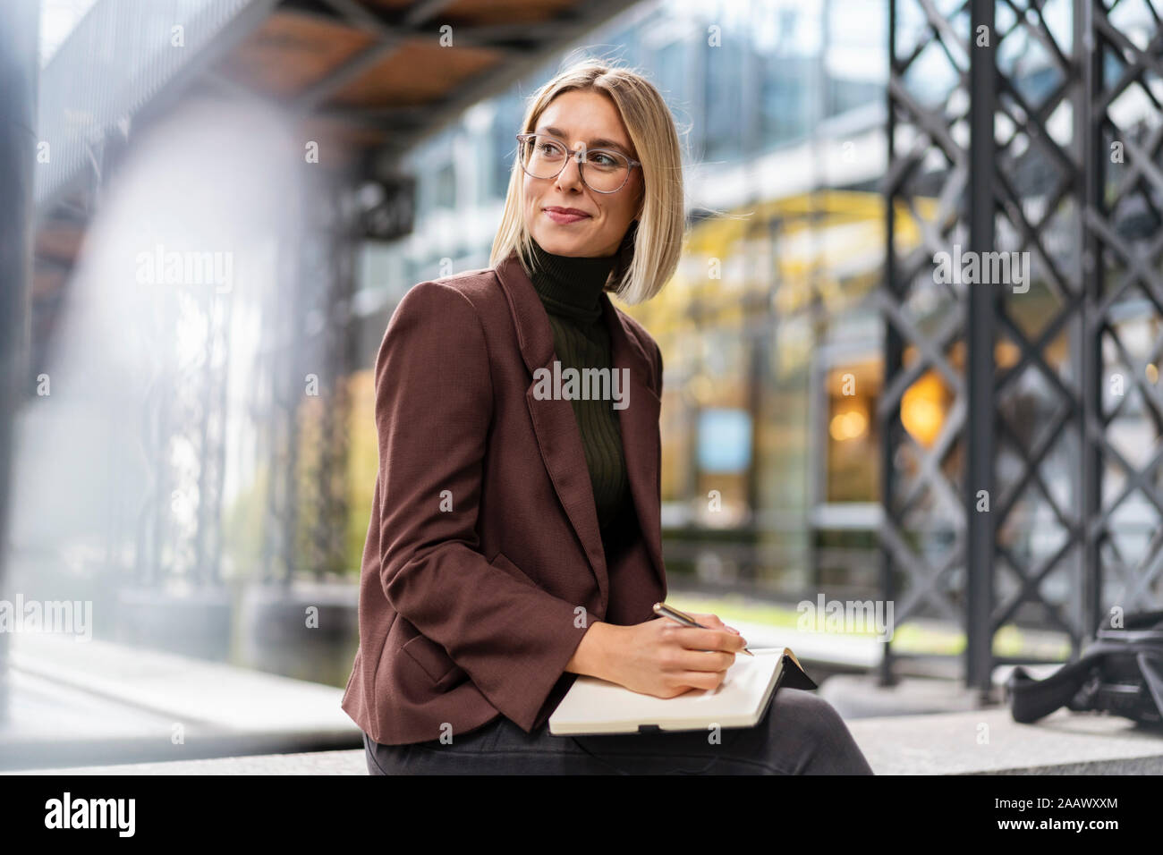 Smiling young businesswoman with notebook in the city Stock Photo