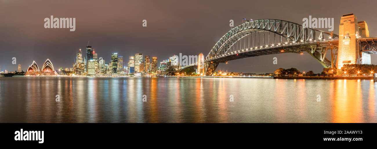 Panoramic shot of illuminated Sydney Harbor Bridge over river at Sydney, Australia Stock Photo