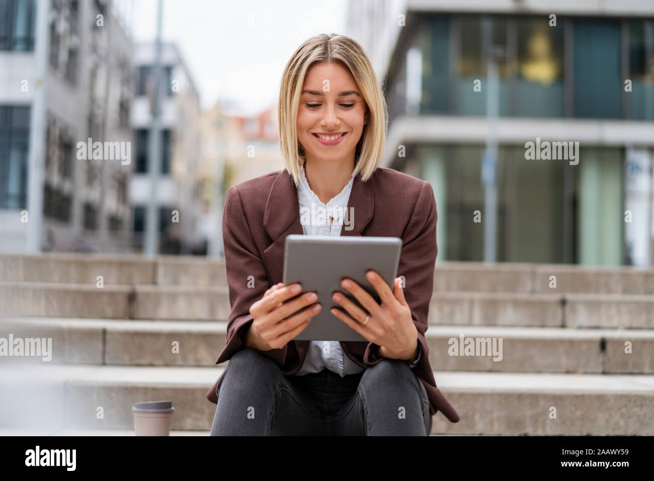 Smiling young businesswoman using tablet in the city Stock Photo