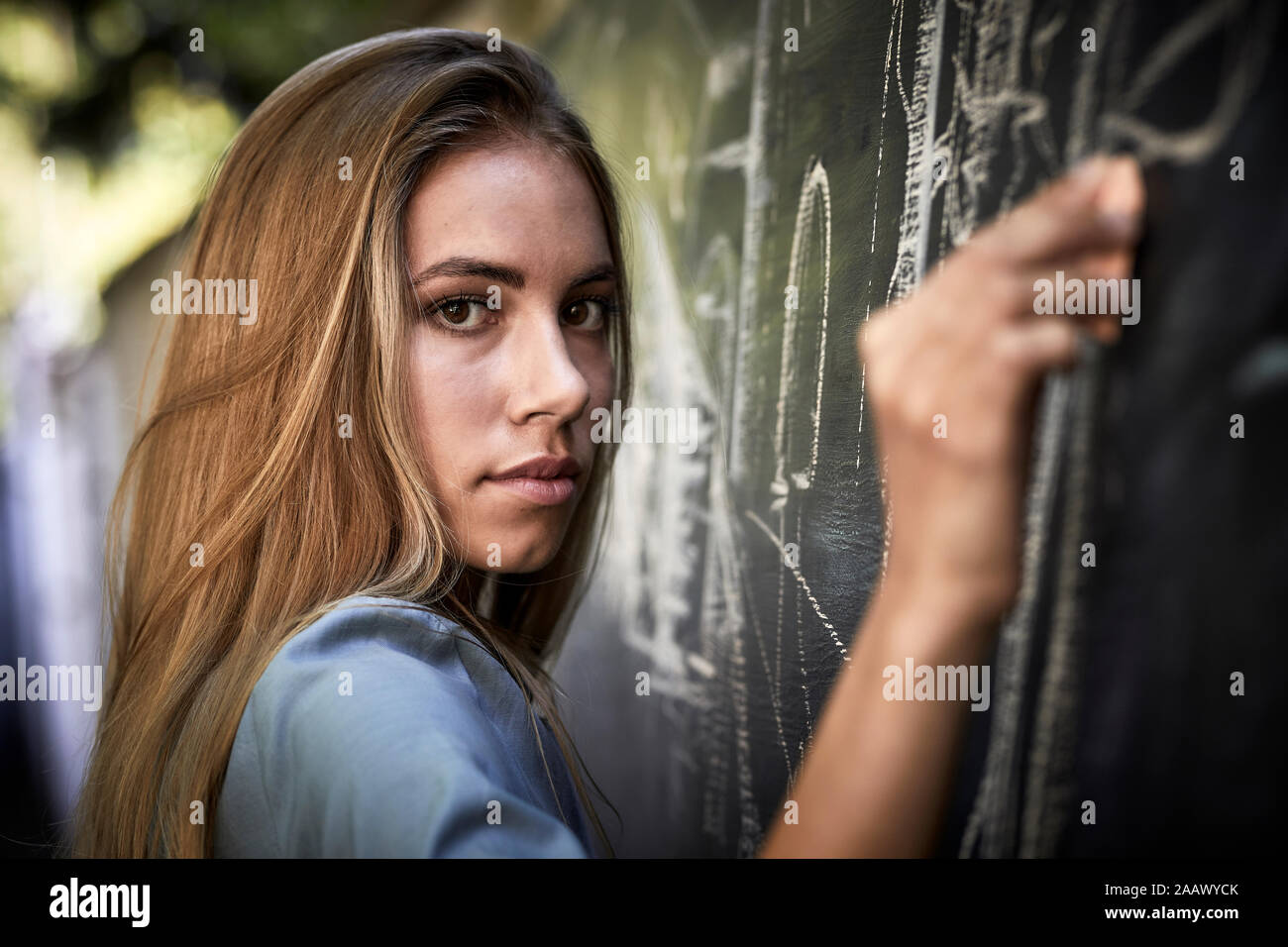 Portrait of a young woman writing on a blackboard Stock Photo