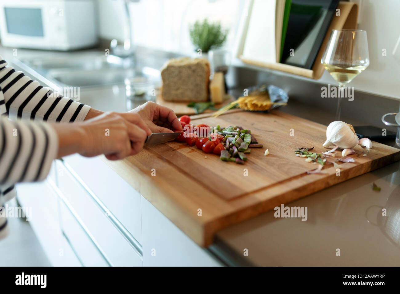 Close-up of woman cooking in kitchen at home cutting vegetables Stock Photo