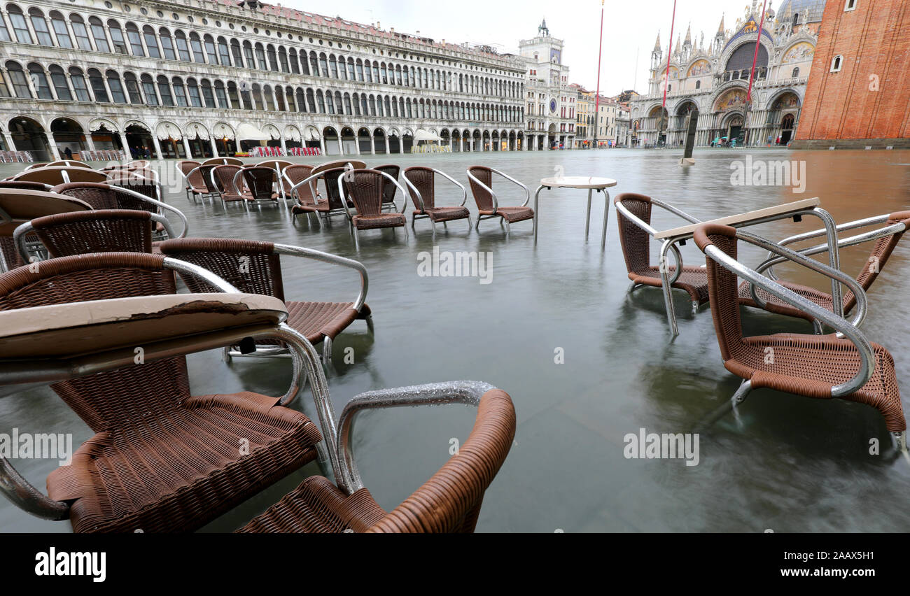 chairs and small tables of sidewalk cafe in Venice Italy with high