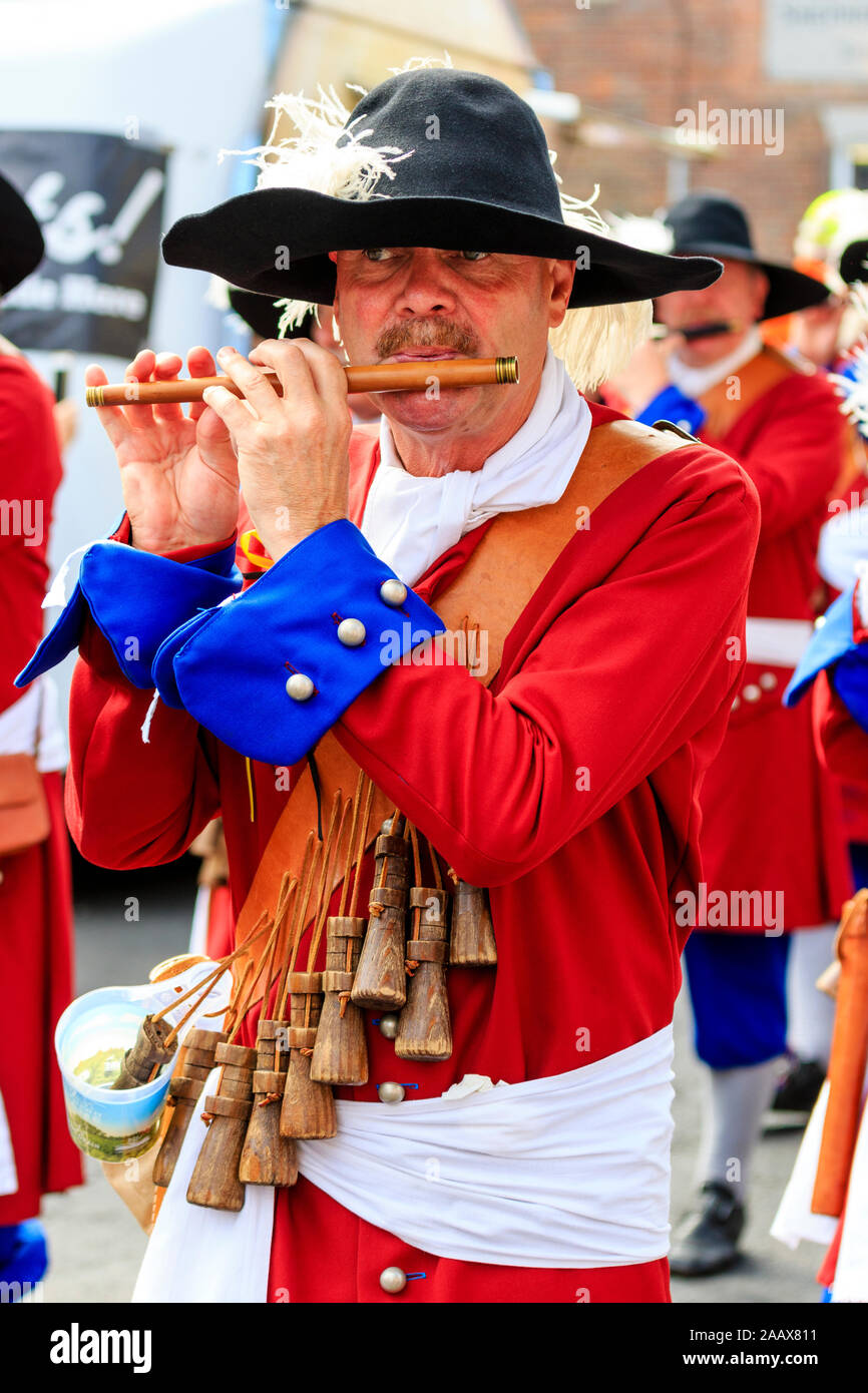 Mature man Flute player from the Dutch Trommelfluit Band marching during a parade at Faversham Hop Festival. Dressed in 17th century orange uniforms. Stock Photo