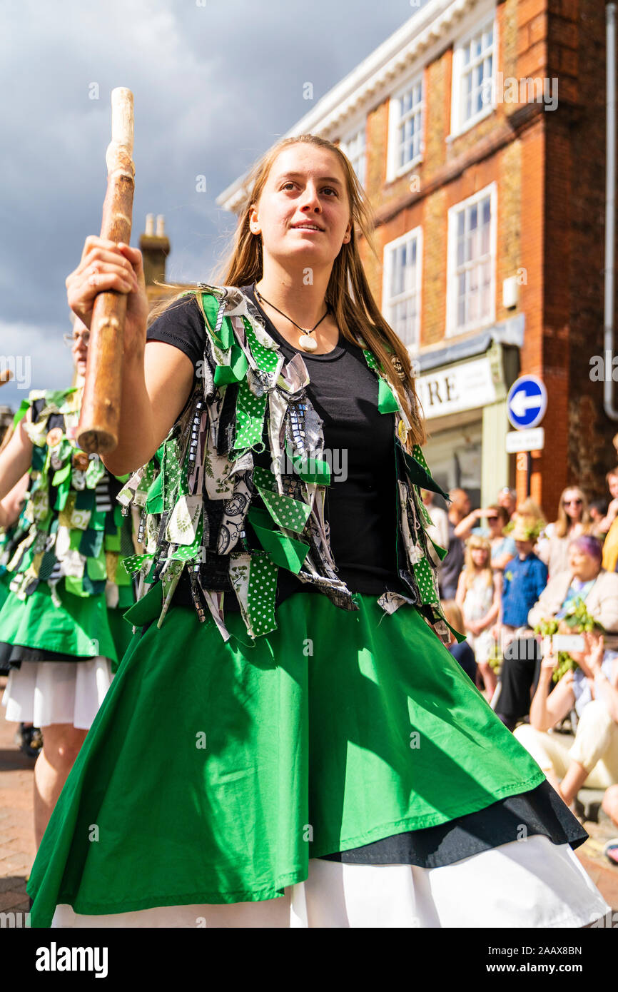 Close up low angle view of young woman from the Offcumduns Morris folk dancers dancing in the street and holding wooden staff at Faversham Hop Festiva Stock Photo