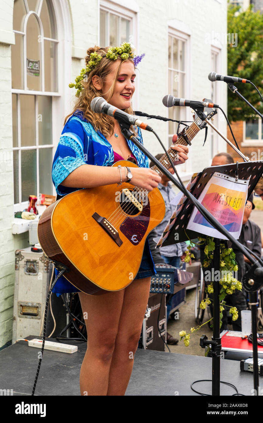 Maisy Beth, young blonde folk singer, singing while playing acoustic