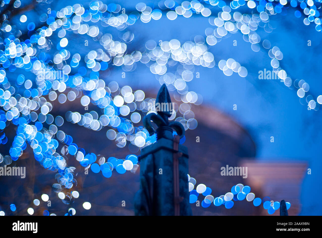 Iron fleur de lis, French lily fence with blue lights bokeh background. Stock Photo