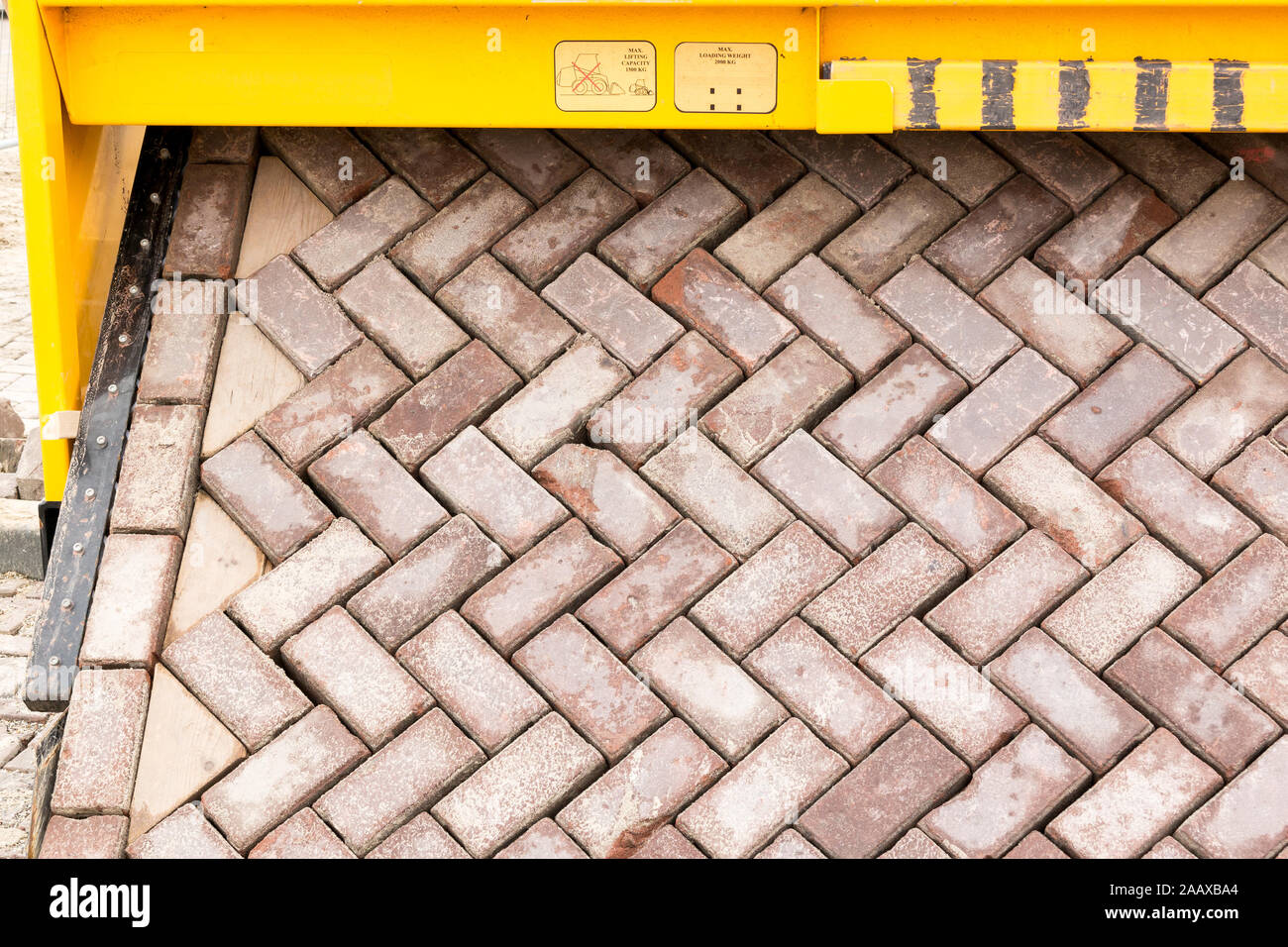 Brick road making machine laying out a carpet of bricks in formation to create new paving on road or street, Netherlands Stock Photo