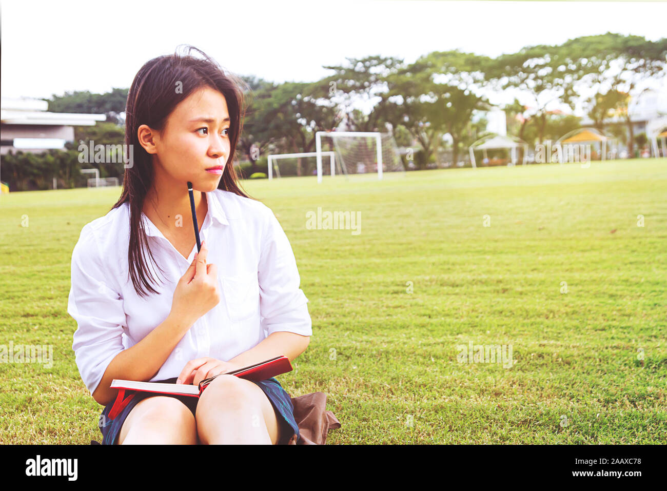 Beautiful young asian girl student thinking a new idea for assignment or project outside the school Stock Photo