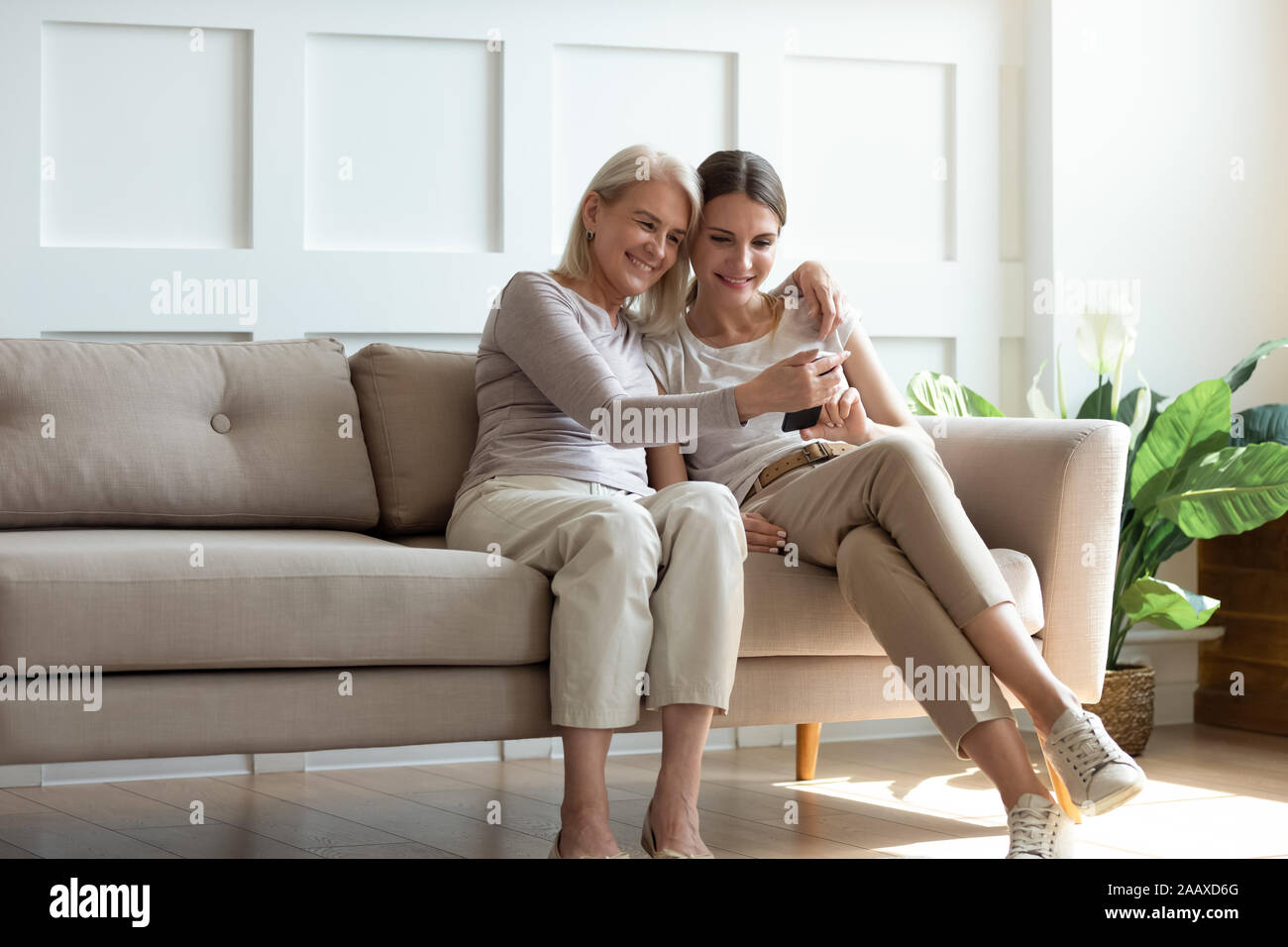 Happy 2 female generations sitting on sofa, enjoying free time. Stock Photo