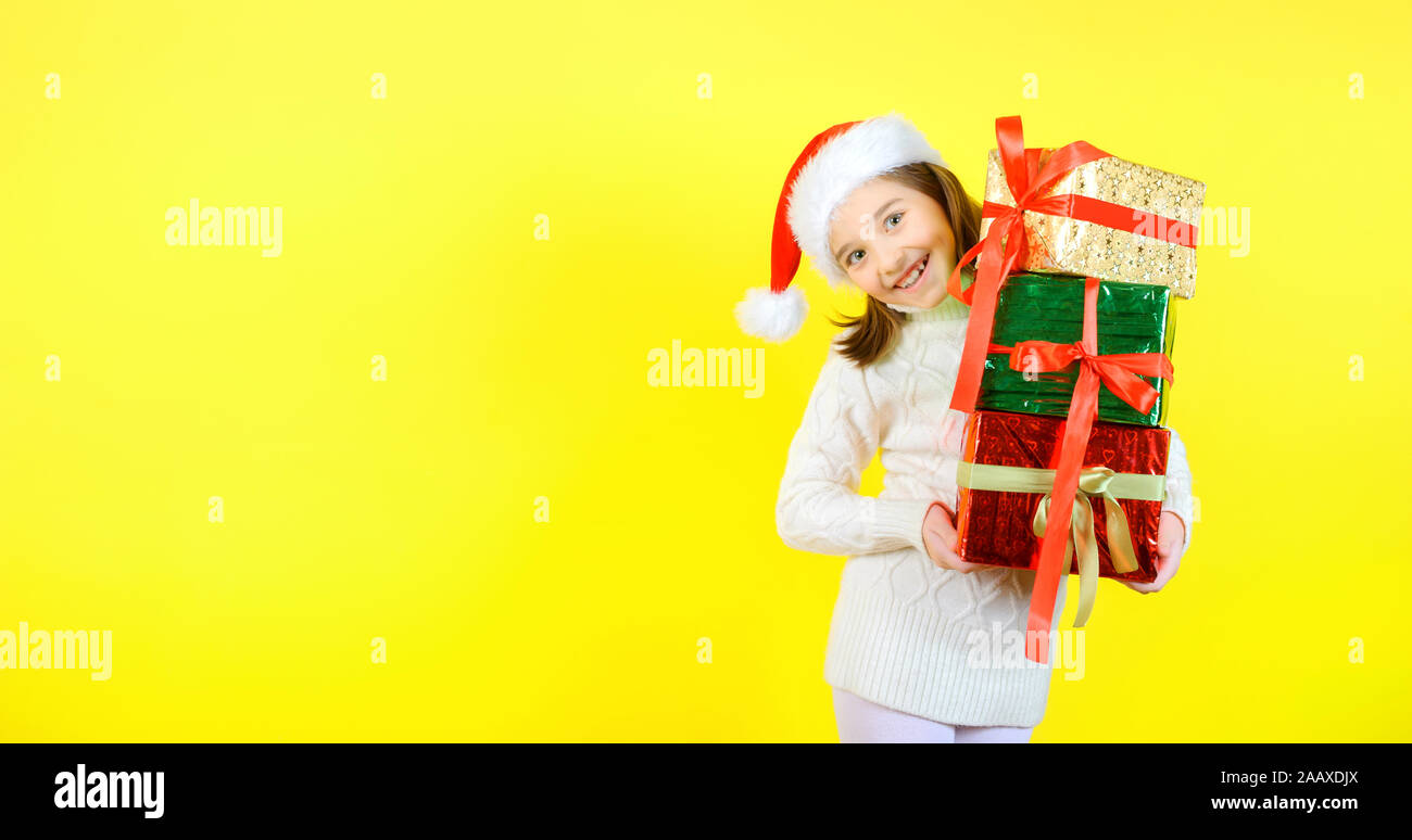 Cute little girl in a santa claus checker holds gift boxes in multi
