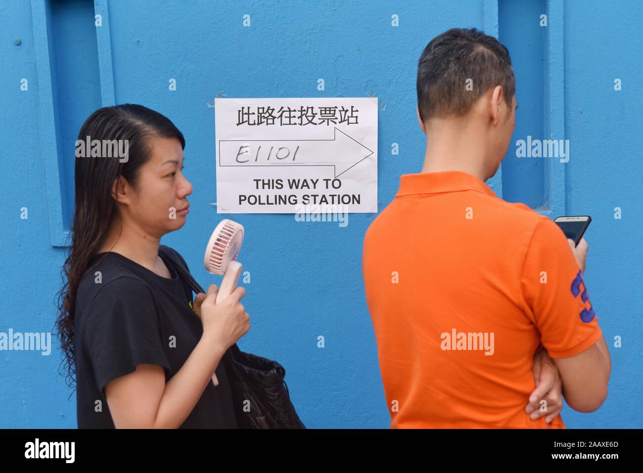 People line up at a polling station to vote in the Mong Kok District Council elections. Hong Kong held its district council election under a rare atmosphere of calm and peace after weeks of intense clashes at numerous universities between anti-government protesters and police which continue into its sixth month of demonstrations. Stock Photo