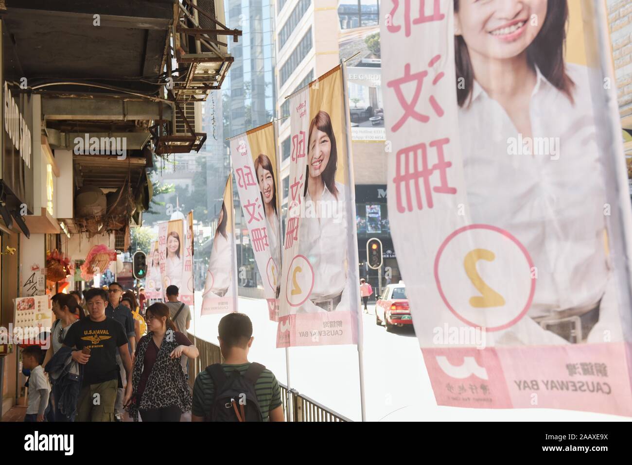 Pedestrians walk past banners of council candidate and ex-police officer Cathy Yau campaigns ahead of District Council Elections. Hong Kong held its district council election under a rare atmosphere of calm and peace after weeks of intense clashes at numerous universities between anti-government protesters and police which continue into its sixth month of demonstrations. Stock Photo