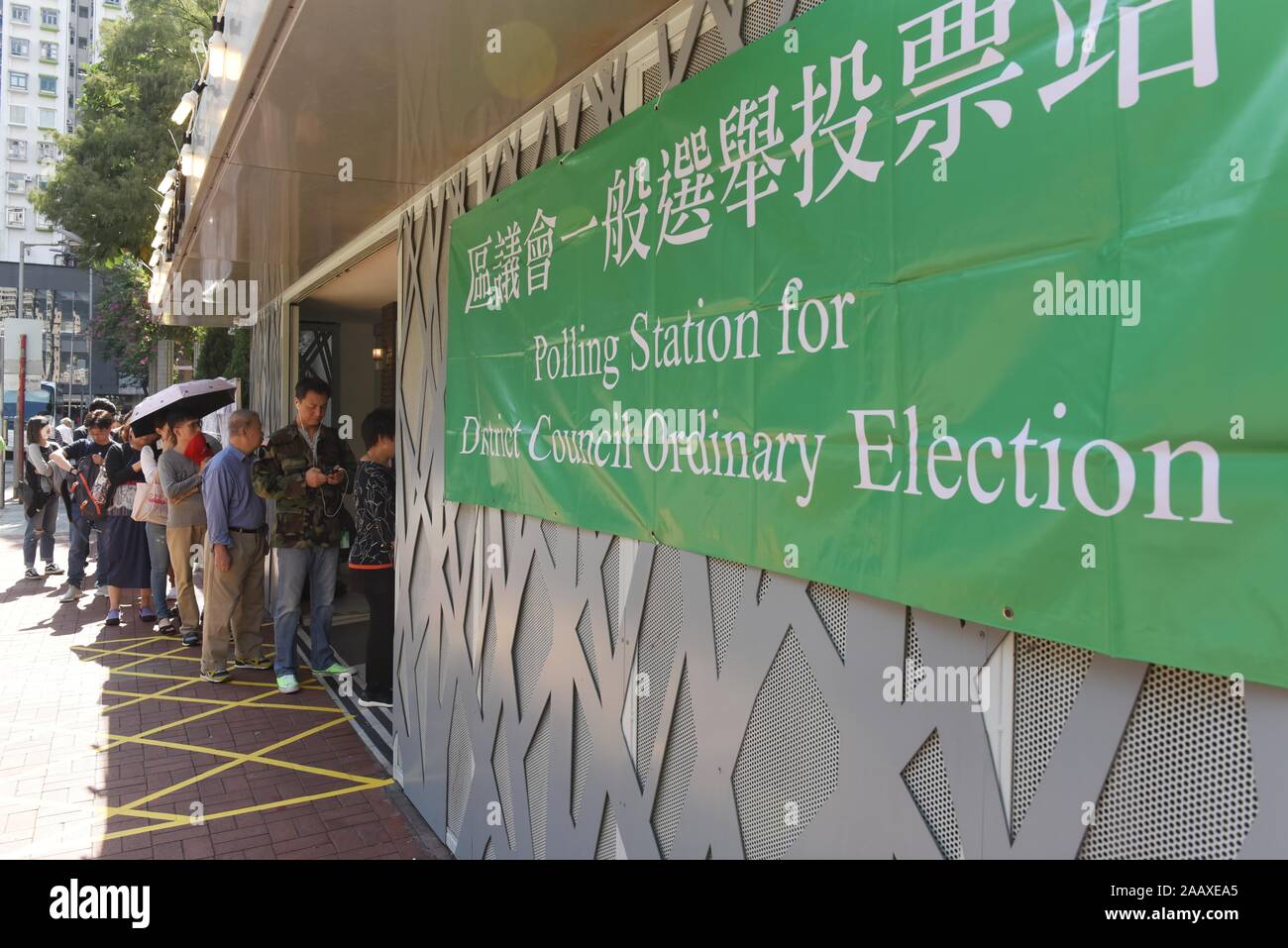 People line up at a polling station to vote in the Mong Kok District Council elections. Hong Kong held its district council election under a rare atmosphere of calm and peace after weeks of intense clashes at numerous universities between anti-government protesters and police which continue into its sixth month of demonstrations. Stock Photo