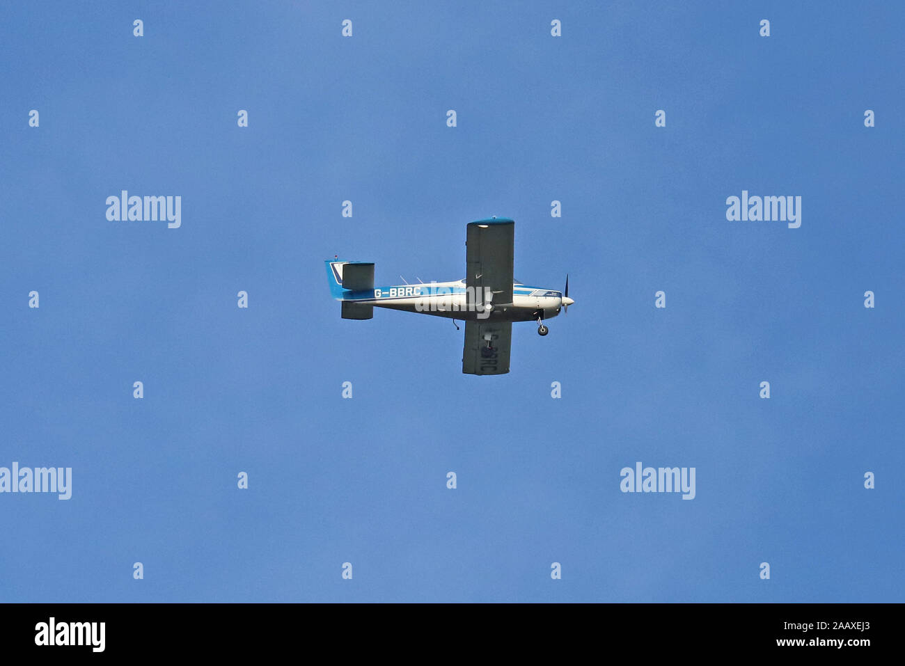 Fuji FA-200-180 a single engined light aircraft G-BBRC flying overhead, set against a blue sky background. Stock Photo