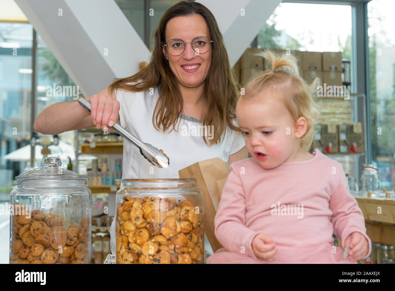 Young mother trying to fill bag with delicious cookies while her mother is eating them. Stock Photo