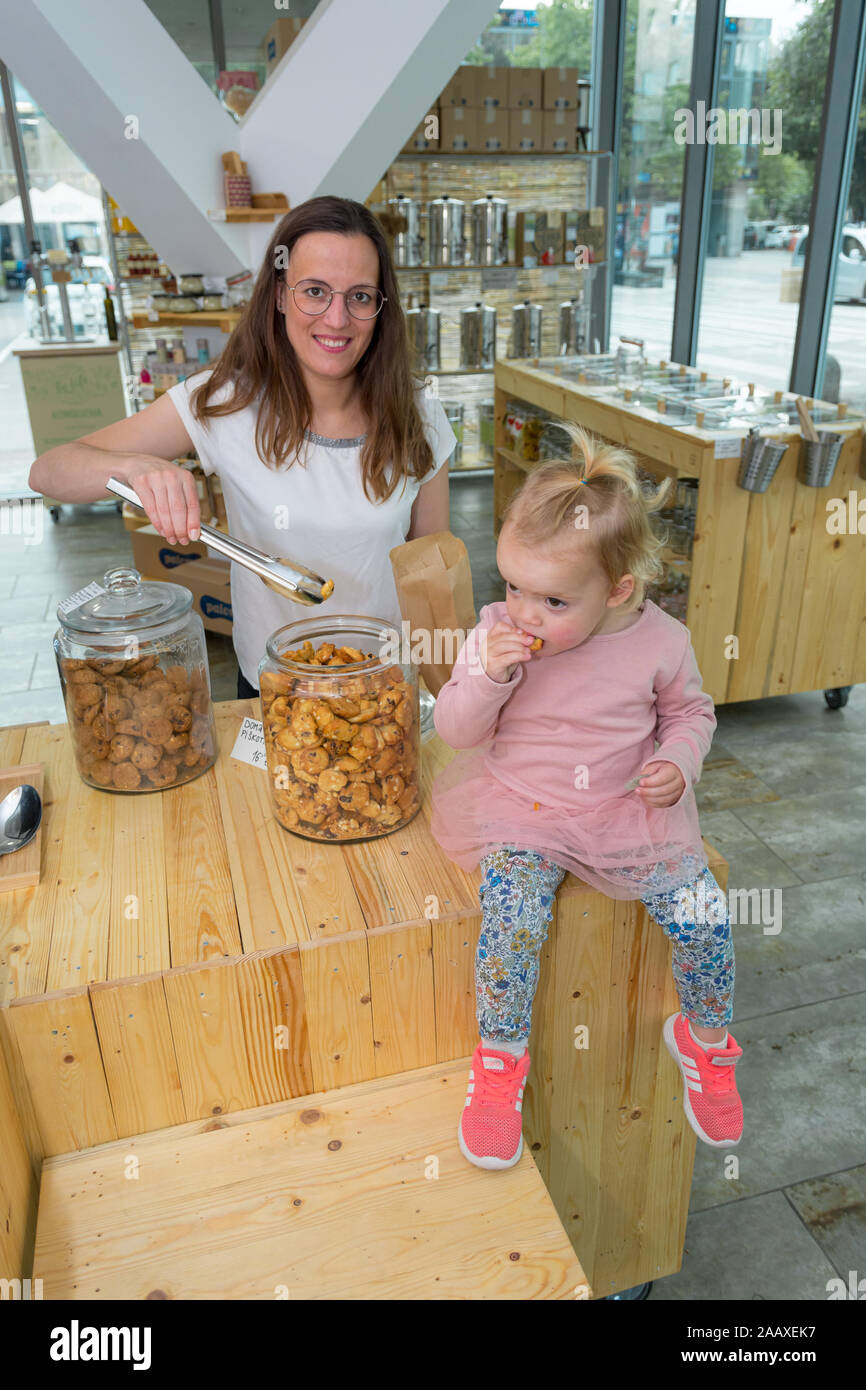 Young mother trying to fill bag with delicious cookies while her mother is eating them. Stock Photo