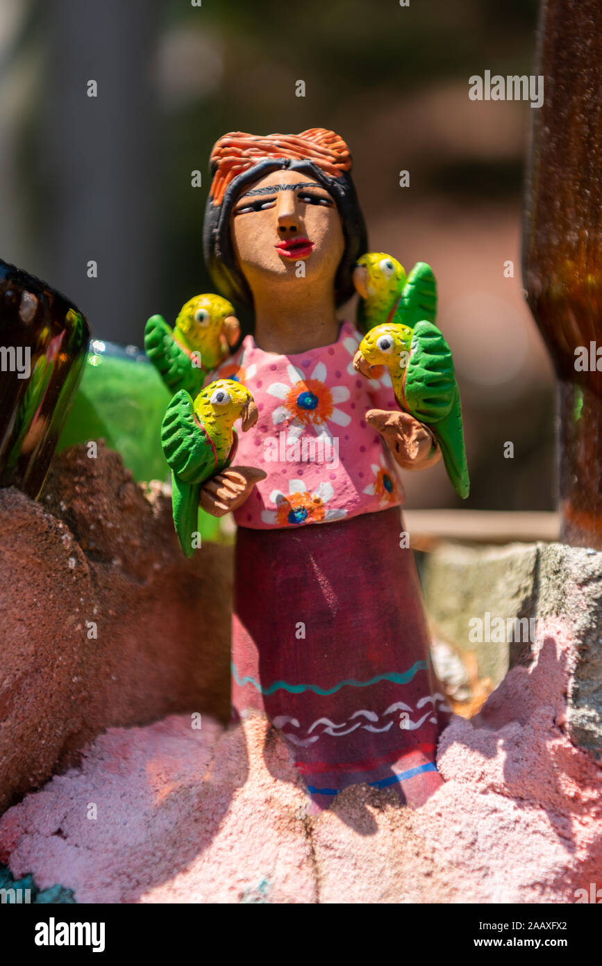 A ceramic sculpture of a woman with parakeets, on a wall in Isaiah