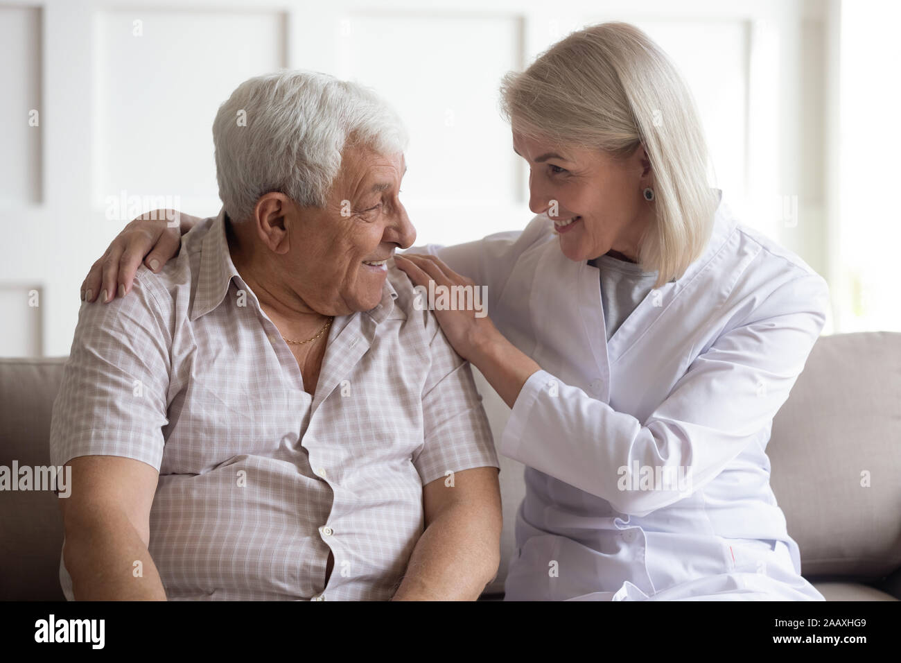 Mature female doctor showing care to elder male patient. Stock Photo