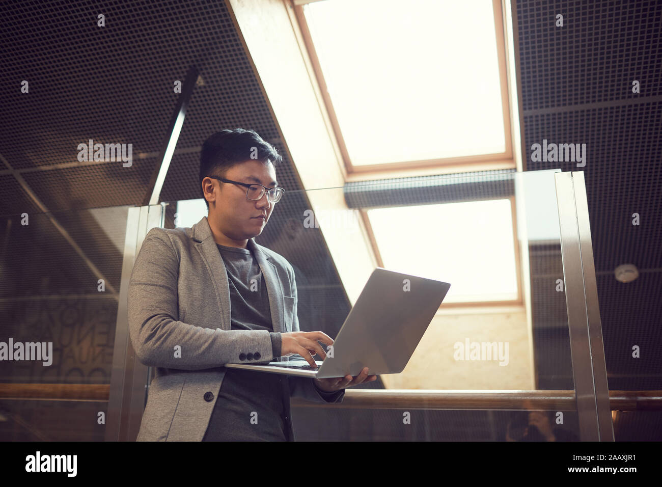 Low angle portrait of successful Asian businessman using laptop while ...