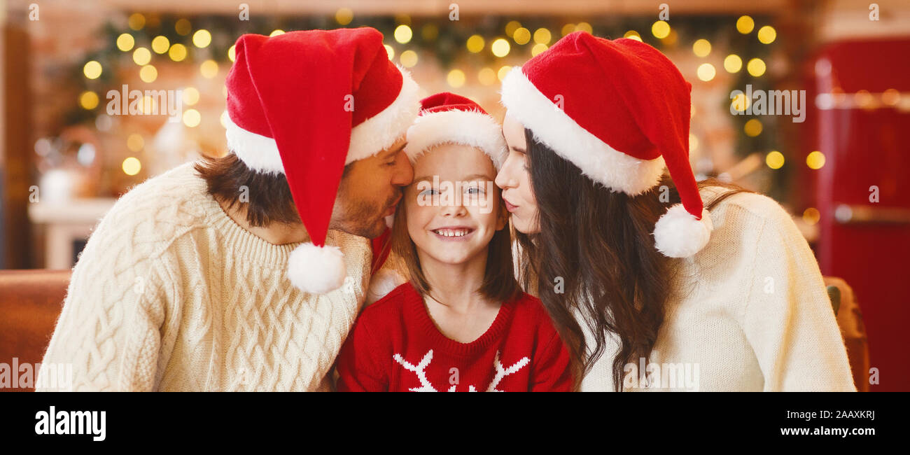 Young mom and dad kissing their little daughter Stock Photo