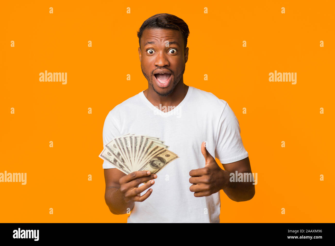 Surprised Black Man Holding Money Gesturing Thumbs-Up Standing, Studio ...